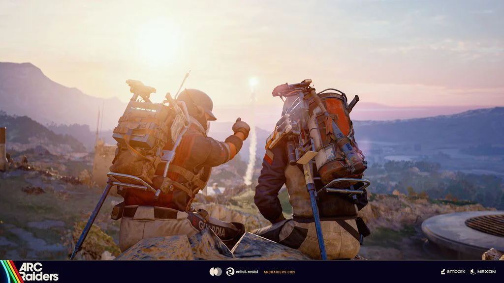 Zwei Raider mit schweren Rucksäcken sitzen bei Sonnenuntergang auf einem Felsen, einer hebt den Daumen